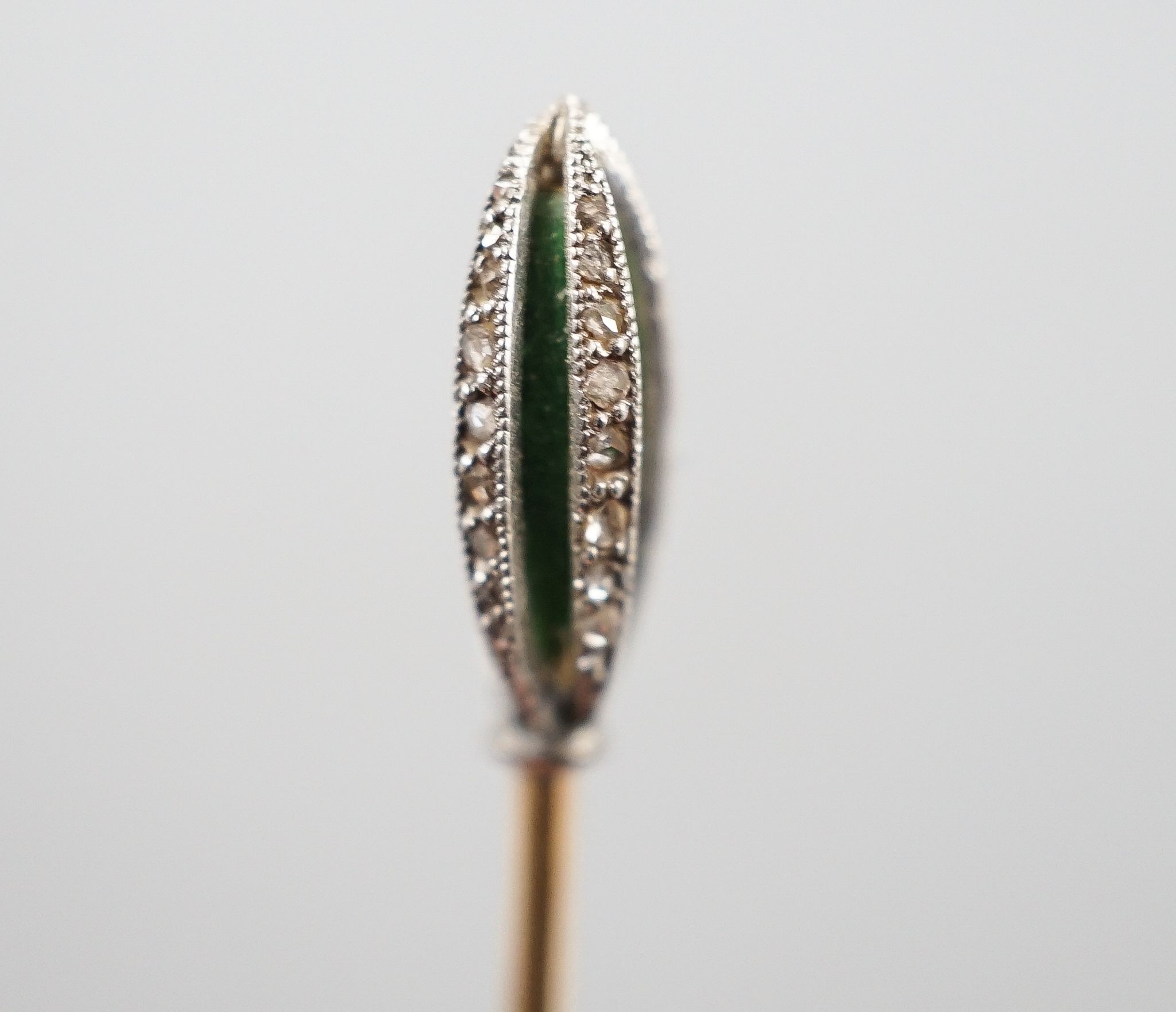 An early 20th century yellow metal stick pin, with rose cut diamond and green enamel set terminal, 76mm, gross weight 2.3 grams.